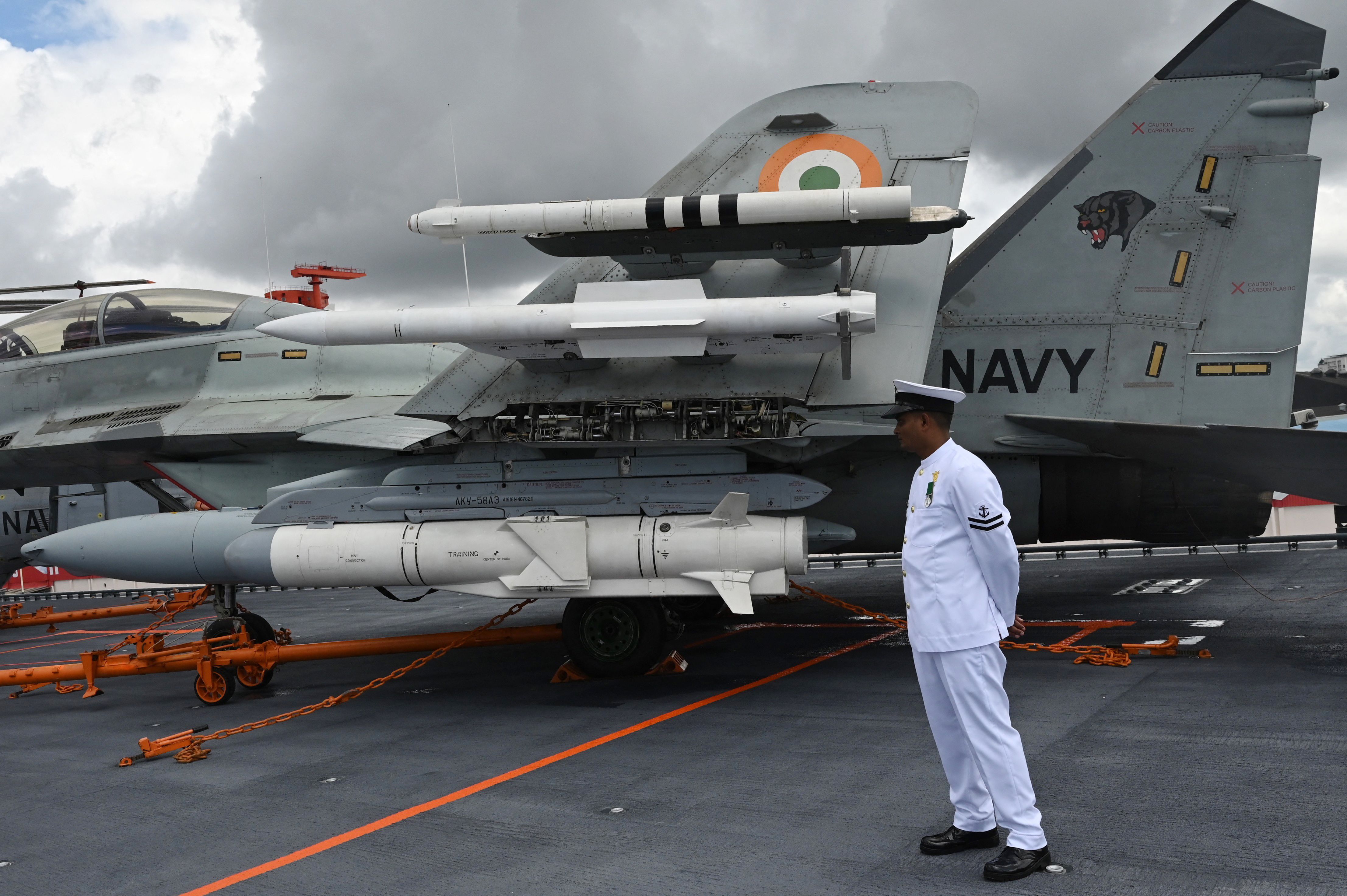 Un officier de la marine indienne se tient à côté d'un avion de combat Mig 29 sur le pont du porte-avions indien INS Vikrant lors de sa mise en service au chantier naval de Cochin à Kochi le 2 septembre 2022. - L'Inde a inauguré son premier porte-avions fabriqué localement le 2 septembre, une étape importante dans les efforts du gouvernement visant à réduire sa dépendance à l'égard des armes étrangères et à contrer l'affirmation militaire croissante de la Chine dans la région. (Photo d'Arun SANKAR / AFP) (Photo d'ARUN SANKAR/AFP via Getty Images)