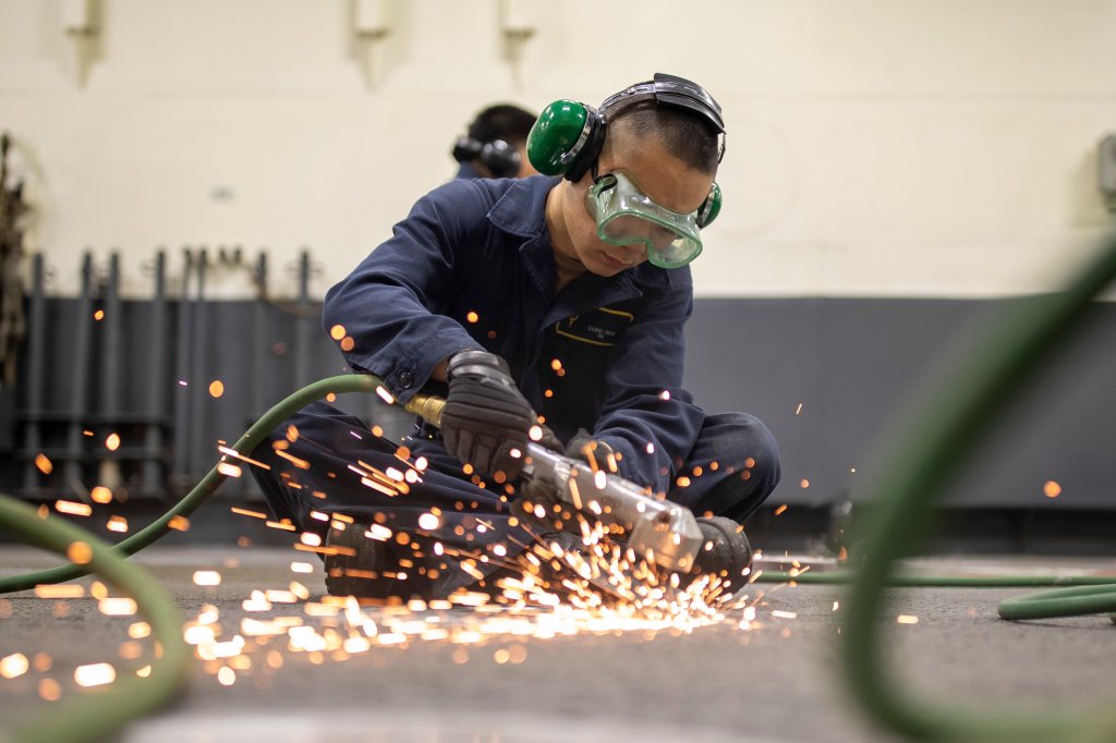 250313-N-KX492-1060 Seaman Dawie Guo, de Monterey Park, Californie, utilise une meuleuse pour enlever la rouille du pont dans la zone de rangement des véhicules à bord du transporteur d'assaut amphibie USS Tripoli (LHA 7), le 13 mars 2025. Tripoli est un navire d'assaut amphibie de classe américaine, porté à San Diego. (Photo de l'US Navy par le matelot Paul LeClair, spécialiste des communications de masse)