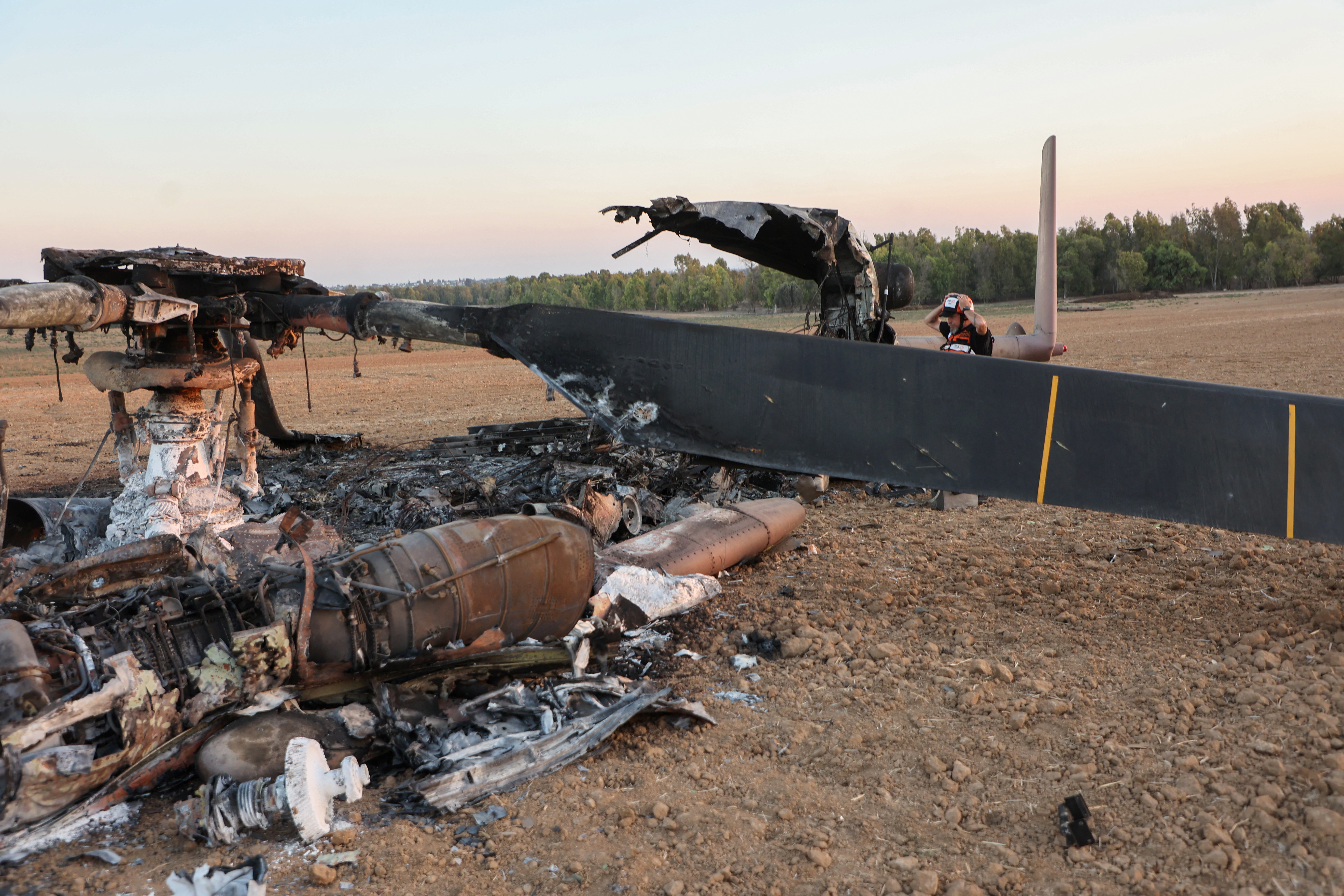 Un membre des services de secours israéliens fouille la carcasse d'un hélicoptère israélien CH-53 « Yasur » le 15 octobre 2023, qui aurait été touché par des militants du Hamas lors de leur attaque une semaine plus tôt et serait tombé du côté israélien de la frontière nord de Gaza. Plus d'un million de personnes ont été déplacées dans la bande de Gaza la semaine dernière, a déclaré l'ONU le 15 octobre, après des bombardements israéliens soutenus et des avertissements concernant une attaque terrestre contre les commandants du Hamas. (Photo de GIL COHEN-MAGEN / AFP) (Photo de GIL COHEN-MAGEN/AFP via Getty Images)