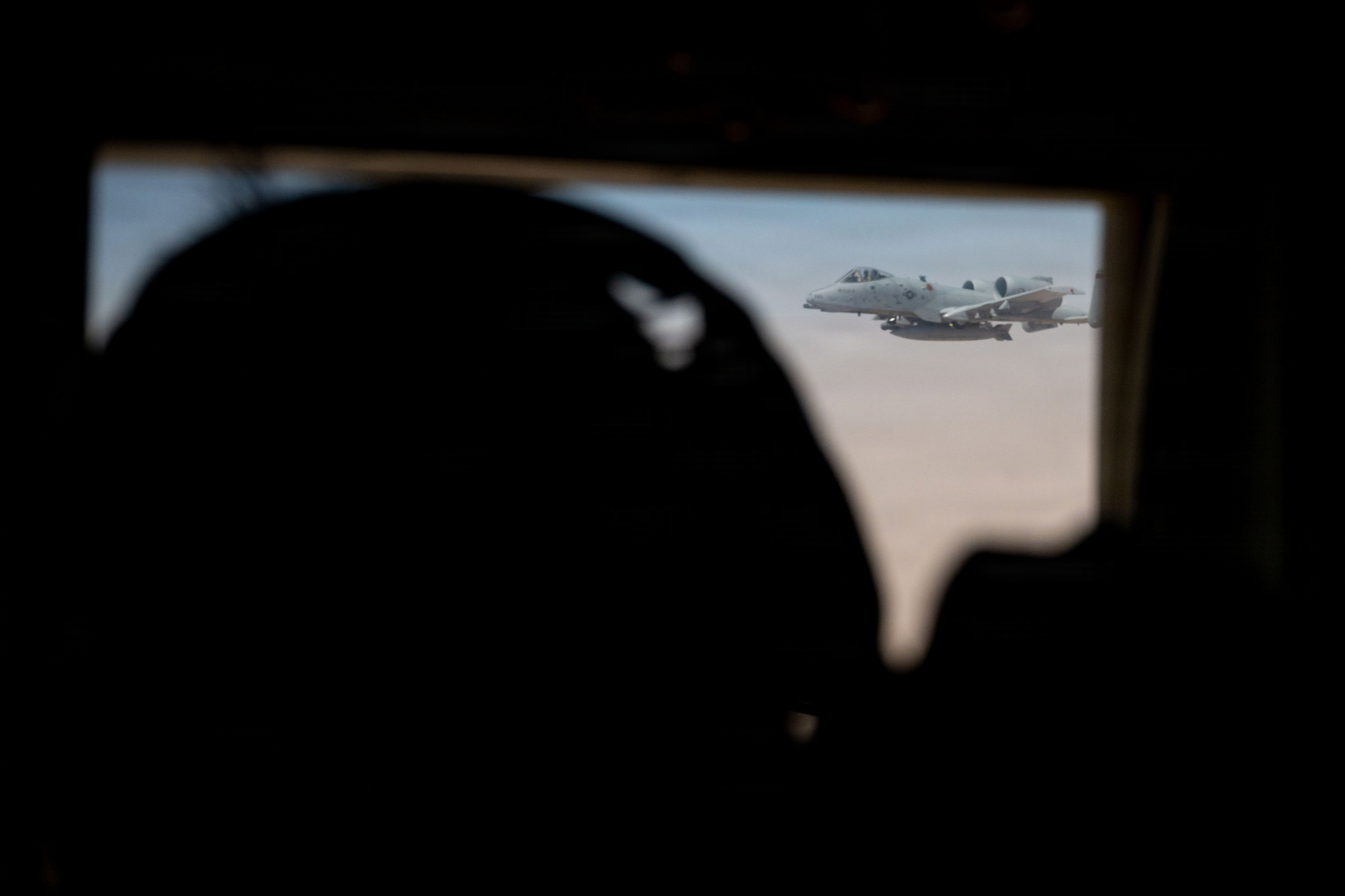 Un arrimeur de l'US Air Force regarde un avion A-10C Thunderbolt II s'approcher de son avion HC-130J Combat King II avant d'effectuer un ravitaillement en vol dans la zone de responsabilité du Commandement central des États-Unis, le 9 mai 2026. (Photo de l'US Air Force)