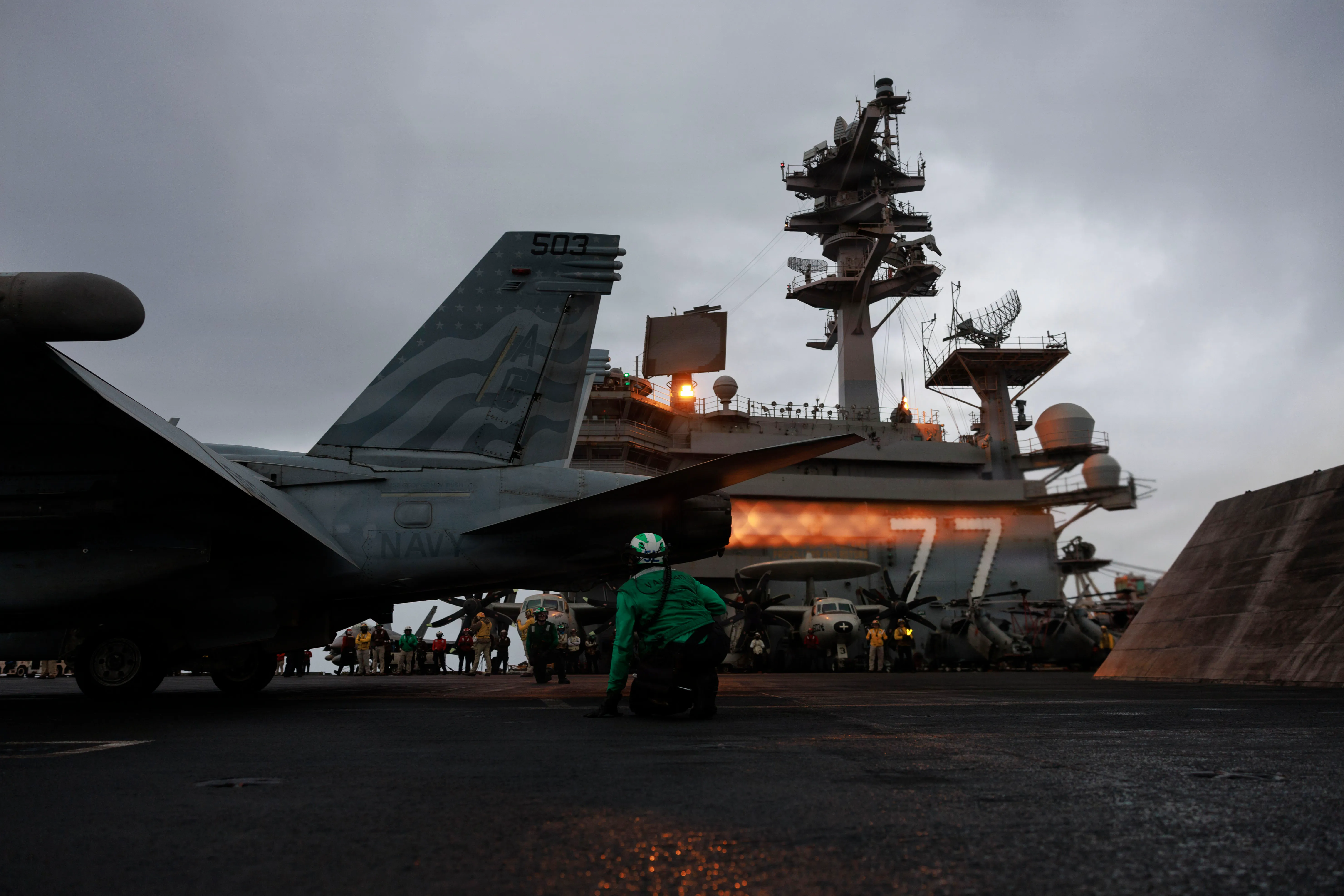 Un marin américain signale un Growler EA-18G, attaché au Escadron d'attaque électronique (VAQ) 140, sur le pont de vol du porte-avions de classe Nimitz USS George HW Bush (CVN 77), le 14 juillet 2026. George HW Bush est déployé dans la zone d'opérations de la 5e flotte américaine pour soutenir la sécurité et la stabilité maritimes au Moyen-Orient. (Photo de la marine américaine)