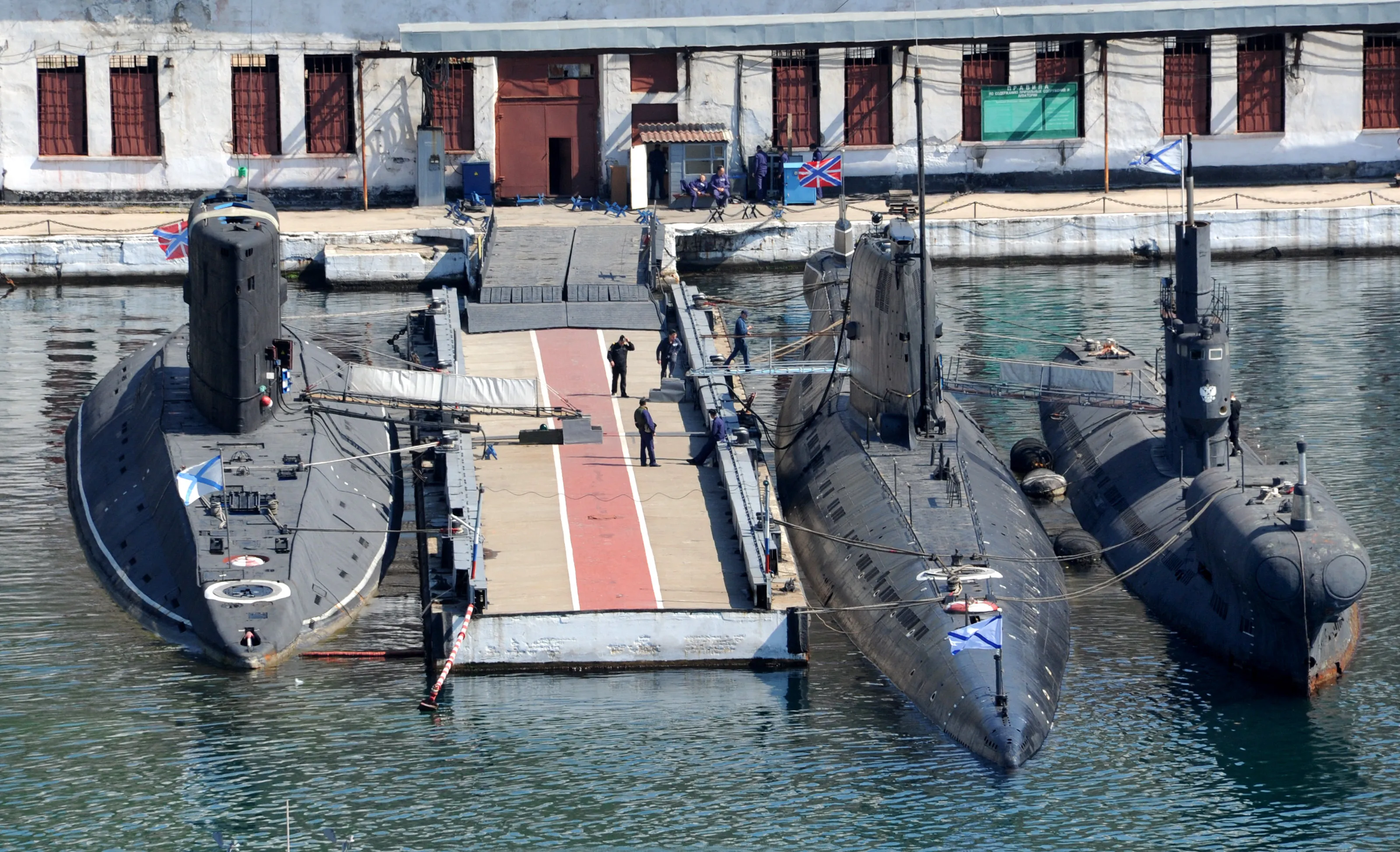 Des drapeaux de la marine russe sont visibles sur l'ancien sous-marin ukrainien Zaporizhzhia (C) amarré entre les sous-marins russes Alrosa (à gauche) et PZS-50 (à droite) dans la baie du port de Crimée de Sébastopol le 27 mars 2014. Les forces maritimes ukrainiennes ont été sévèrement diminuées par l'intervention russe en Crimée après avoir perdu 12 de leurs 17 navires de guerre au profit de Moscou, dont le seul diesel-électrique de classe Foxtrot d'Ukraine. sous-marin des années 1970, le Zaporizhzhia, ont déclaré les analystes de la défense Jane's. PHOTO AFP/ VIKTOR DRACHEV (Photo de VIKTOR DRACHEV / AFP) (Photo de VIKTOR DRACHEV/AFP via Getty Images)