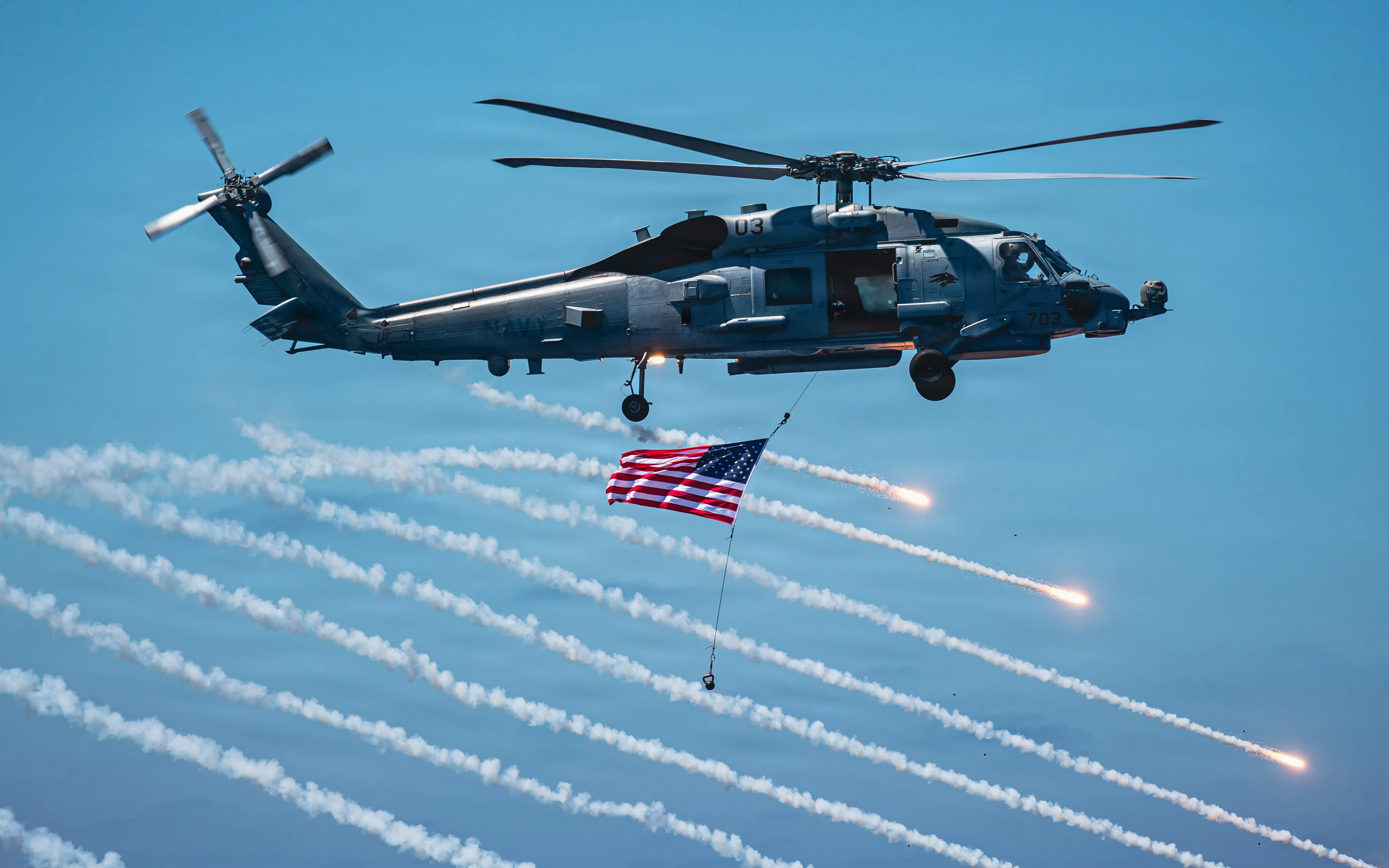 L'hélicoptère Seahawk MH-60R de la Marine américaine, affecté à l'Escadron d'hélicoptères de frappe maritime (HSM) 75, tire des fusées éclairantes tout en survolant le pont de vol du porte-avions de classe Nimitz USS Theodore Roosevelt (CVN) 71 lors d'une croisière d'une journée entre amis et famille, le 8 août 2026. La croisière d'une journée entre amis et famille de Theodore Roosevelt met en valeur les capacités du groupe de grève des transporteurs et le professionnalisme de l'équipage. (Photo de l'US Navy par le matelot Tyler Harstad, spécialiste des communications de masse)