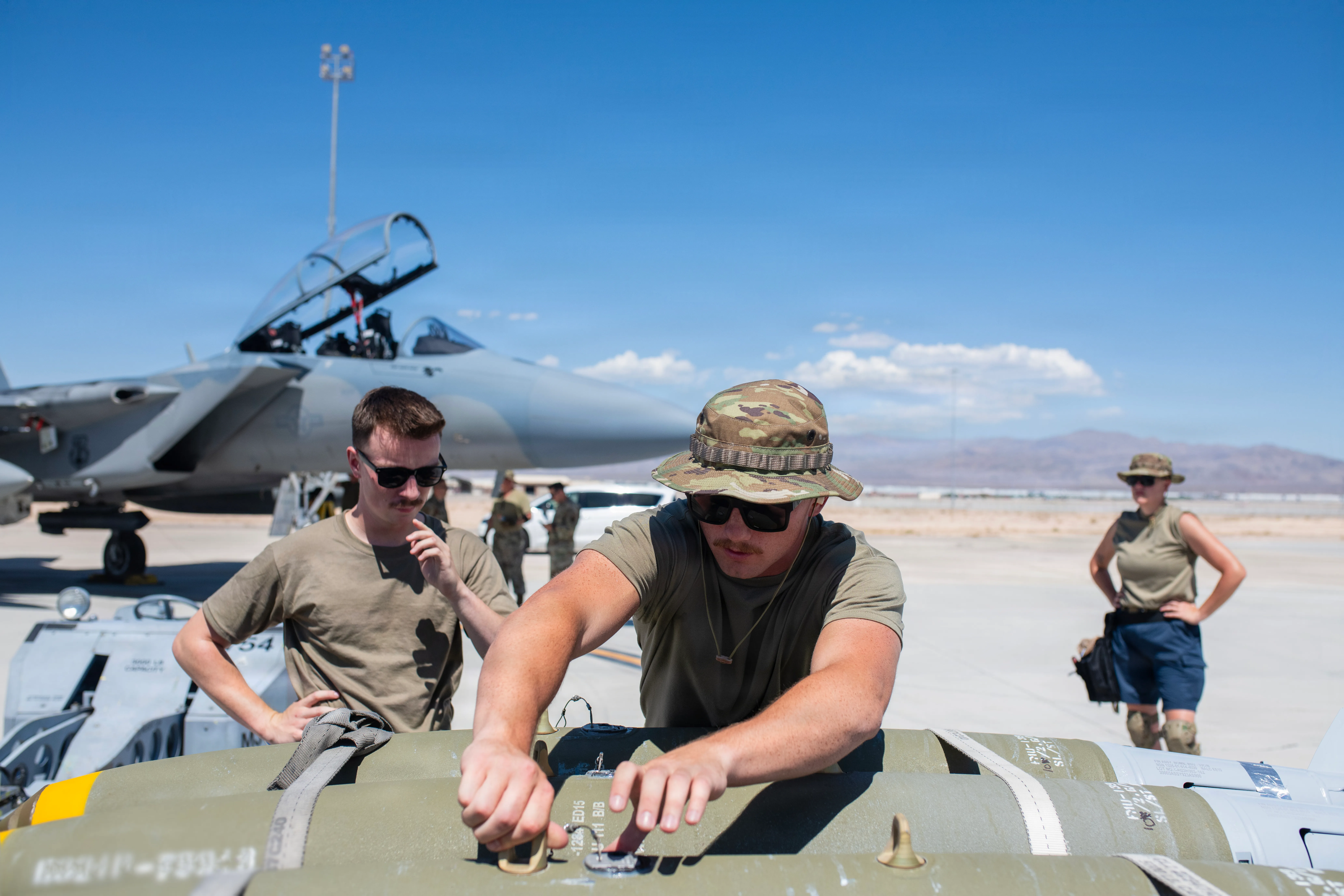 Le sergent d'état-major de l'US Air Force. Parker Mayhew (au centre), un chargeur d'armes affecté au 142e Escadron de maintenance d'aéronefs, prépare une bombe à charger sur un avion F-15EX Eagle II sous le regard de l'Airman principal de l'US Air Force Alexander Walker (à gauche), le 26 août 2026, base aérienne de Nellis, Nevada. La flotte de F-15EX de la 142e Escadre a opéré depuis Nellis AFB pendant trois semaines fin août et début septembre dans le cadre du cours d'instructeur d'armes (WIC) de l'US Air Force. Pendant ce temps, l'unité a franchi une étape historique en larguant pour la première fois des bombes réelles depuis des F-15EX opérationnels. (Photo de la Garde nationale aérienne des États-Unis par le sergent-chef. Steph Sawyer)
