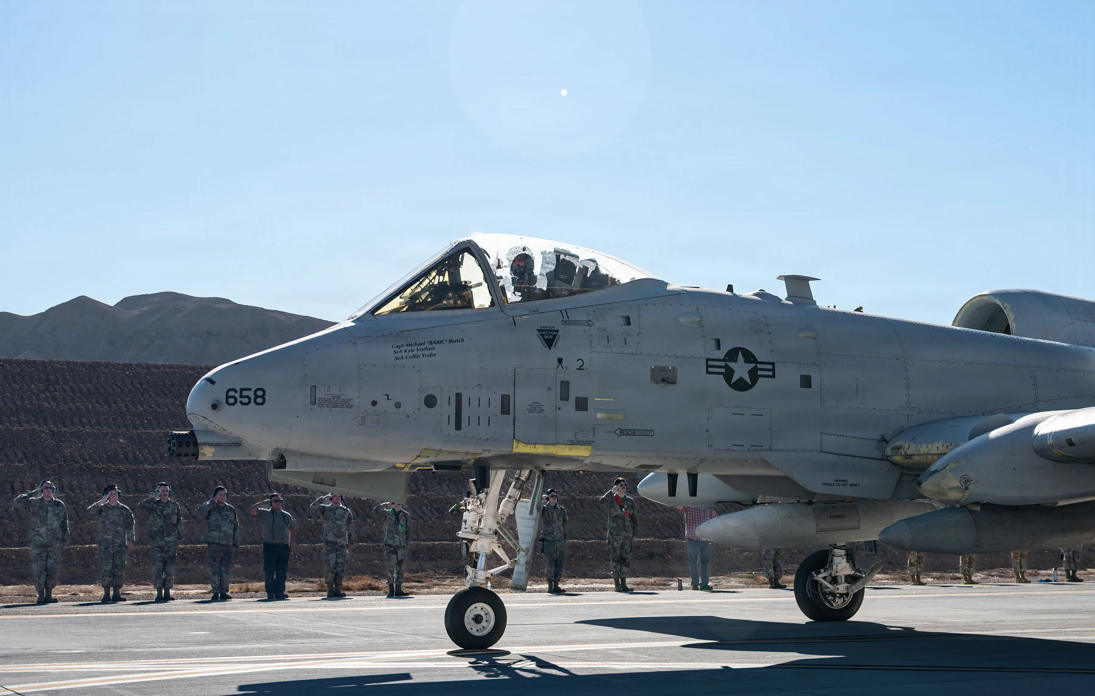 Des aviateurs américains affectés à la base aérienne de Nellis saluent un avion A-10 Thunderbolt II à la base aérienne de Nellis, Nevada, le 22 septembre 2026. Le vol a marqué le départ final du dernier A-10 de Nellis et a honoré près d'un demi-siècle de service d'appui aérien rapproché ainsi que les responsables de la maintenance, les pilotes et le personnel de soutien qui ont maintenu la flotte prête à la mission. (Photo de l'US Air Force par l'aviateur Isabella Borrillo)