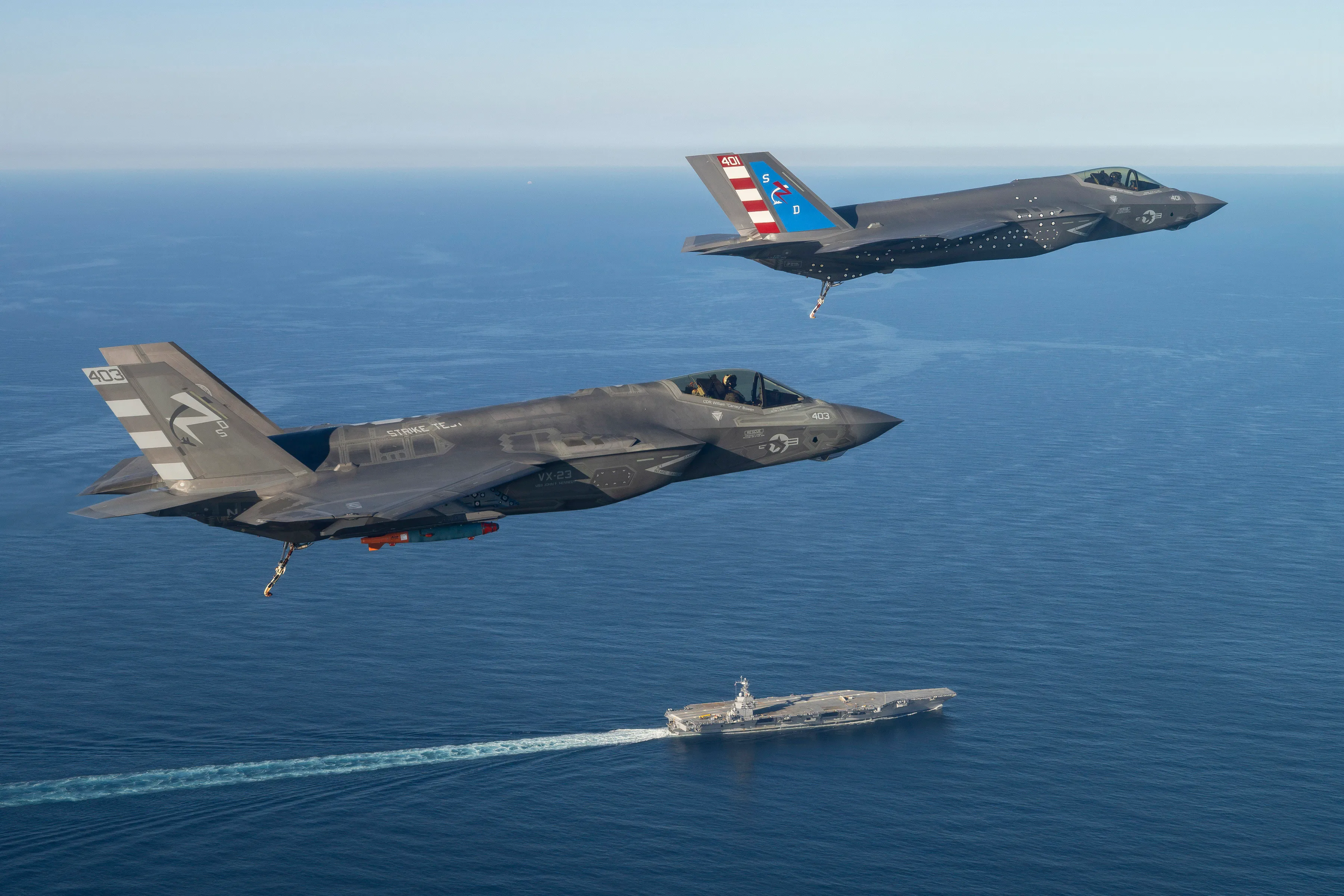 Deux pilotes d'essai F-35 de l'Escadron d'essais et d'évaluation aériens deux trois (VX-23), Division des aéronefs du Centre de guerre aérienne navale (NAWCAD), volent des avions de combat F-35C Lightning II jusqu'au PCU John F. Kennedy (CVN 79) dans l'Atlantique Ouest le 13 octobre 2026. C'est la première fois qu'un F-35C atterrit sur un porte-avions de classe Ford. Une équipe de la Force de test intégrée (ITF) du Patuxent River F-35 détachée sur le navire effectue des tests de compatibilité des aéronefs (ACT) avec la variante porte-avions spécialement instrumentée du jet furtif. ACT évalue les capacités opérationnelles des équipements de lancement et de récupération des avions du navire avec les avions de l'US Navy.