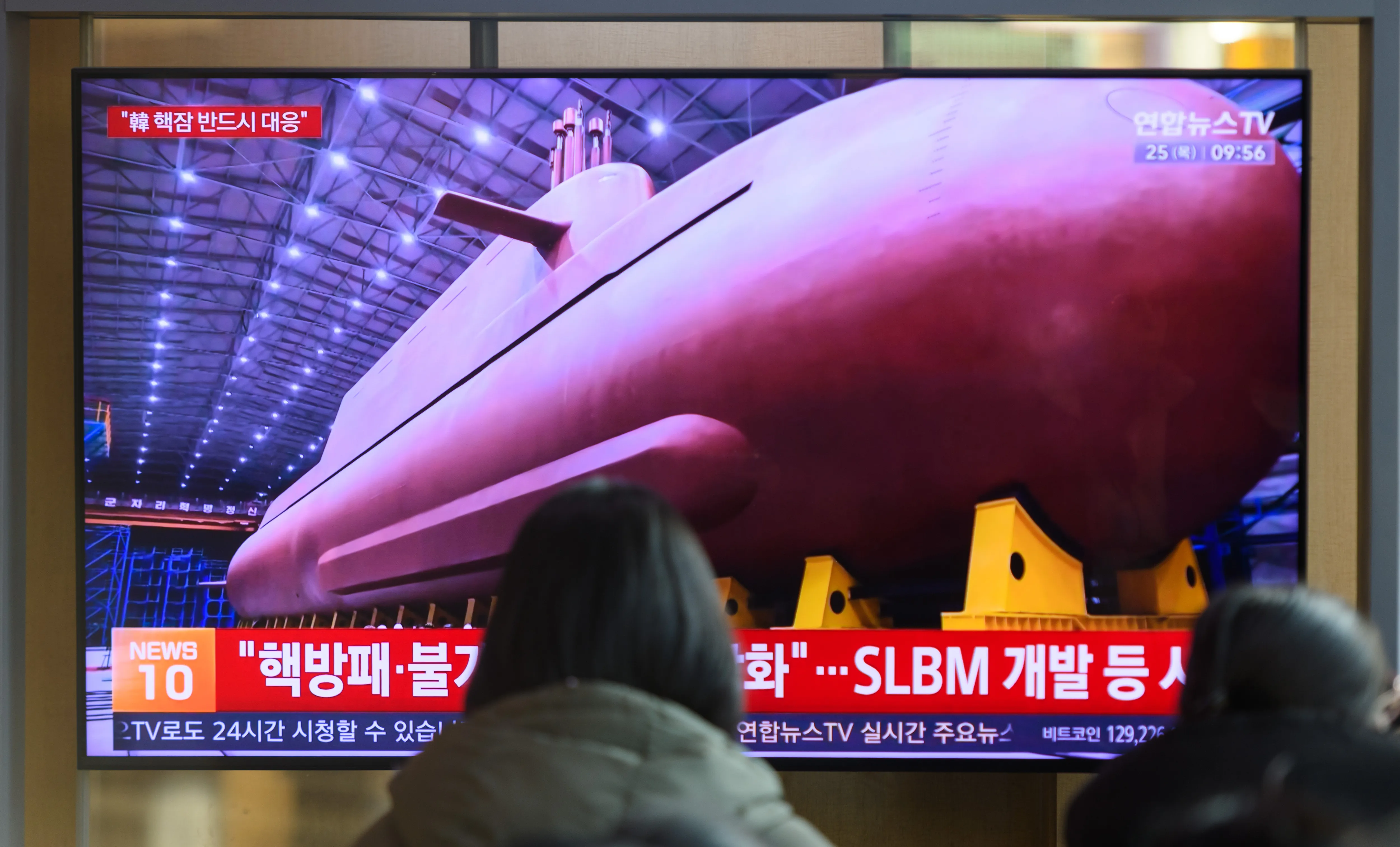 SÉOUL, CORÉE DU SUD - 2025/12/25 : Des personnes ont vu une émission télévisée d'information Yonhap diffusée 24 heures sur 24 à la gare de Séoul, montrant une émission d'information montrant le dirigeant nord-coréen Kim Jong Un voilant le site de fabrication d'un sous-marin à missiles guidés stratégiques à propulsion nucléaire de 8 700 tonnes dans un lieu inconnu. Le dirigeant nord-coréen Kim Jong Un a déclaré que le projet sud-coréen de construire des sous-marins à propulsion nucléaire "aggraver l'instabilité" dans la région, qualifiant la décision de la Corée du Sud de menace pour la sécurité nationale du Nord, selon les médias officiels du 25 décembre. Le dirigeant nord-coréen Kim Jong Un a fait ces remarques lors d'une inspection sur place d'un sous-marin à missiles guidés stratégiques à propulsion nucléaire de 8 700 tonnes en construction, a déclaré l'Agence centrale de presse coréenne (KCNA). (Photo de Kim Jae-Hwan/SOPA Images/LightRocket via Getty Images)