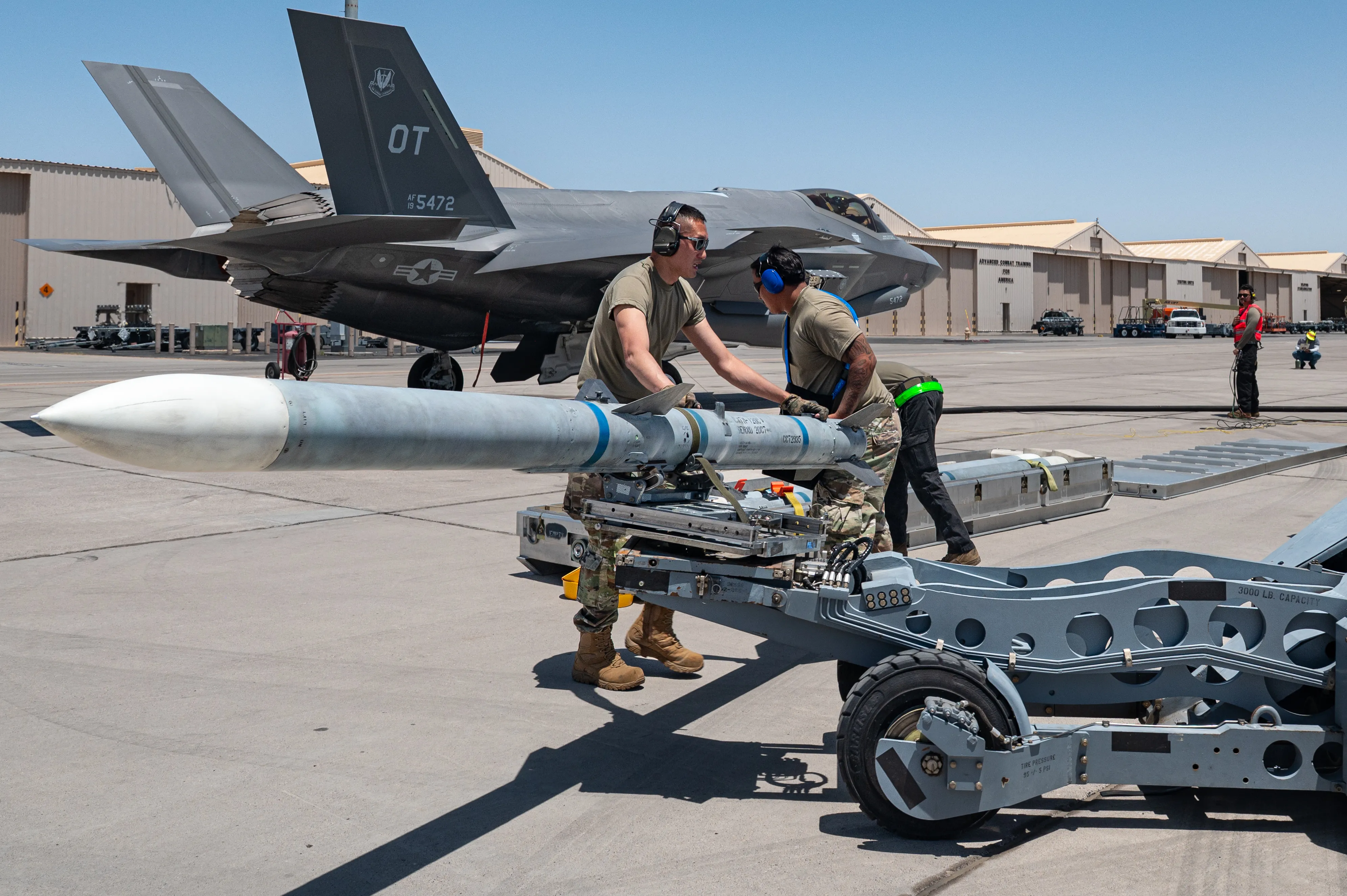 Le sergent d'état-major de l'US Air Force. Andrew Wilson, à gauche, chef d'équipe de chargement d'armes, et l'Airman principal Anthony Silva, membre d'équipage de chargement d'armes, affecté à l'unité de maintenance d'aéronefs Bolt du 57e Escadron de maintenance d'aéronefs, fixent une munition sur un camion élévateur de bombes lors d'un exercice de virage de combat intégré (TIC) à chaud à la base aérienne de Nellis, Nevada, le 23 juin 2025. Pendant les TIC chaudes, quatre missiles air-air avancés à moyenne portée AIM-120 sont chargés sur un F-35 Lightning II tandis que l'avion est ravitaillé simultanément avec ses moteurs en marche. (Photo de l'US Air Force par William R. Lewis)
